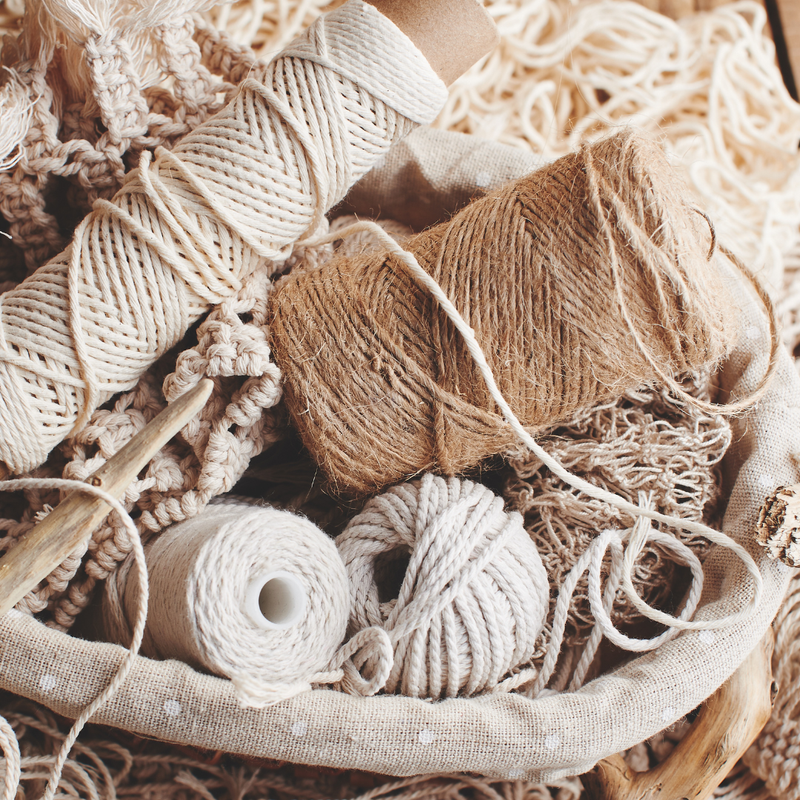Basket filled with beige and brown yarn balls on a wooden surface