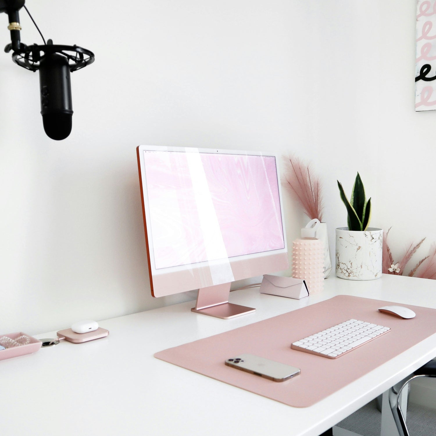 Modern home office desk setup with computer, microphone, and decor.